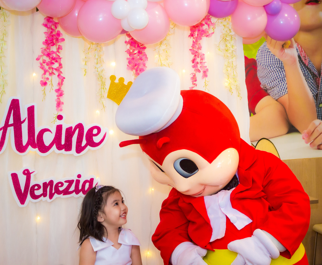 Photo of a kid and jollibee mascot smiling to each other