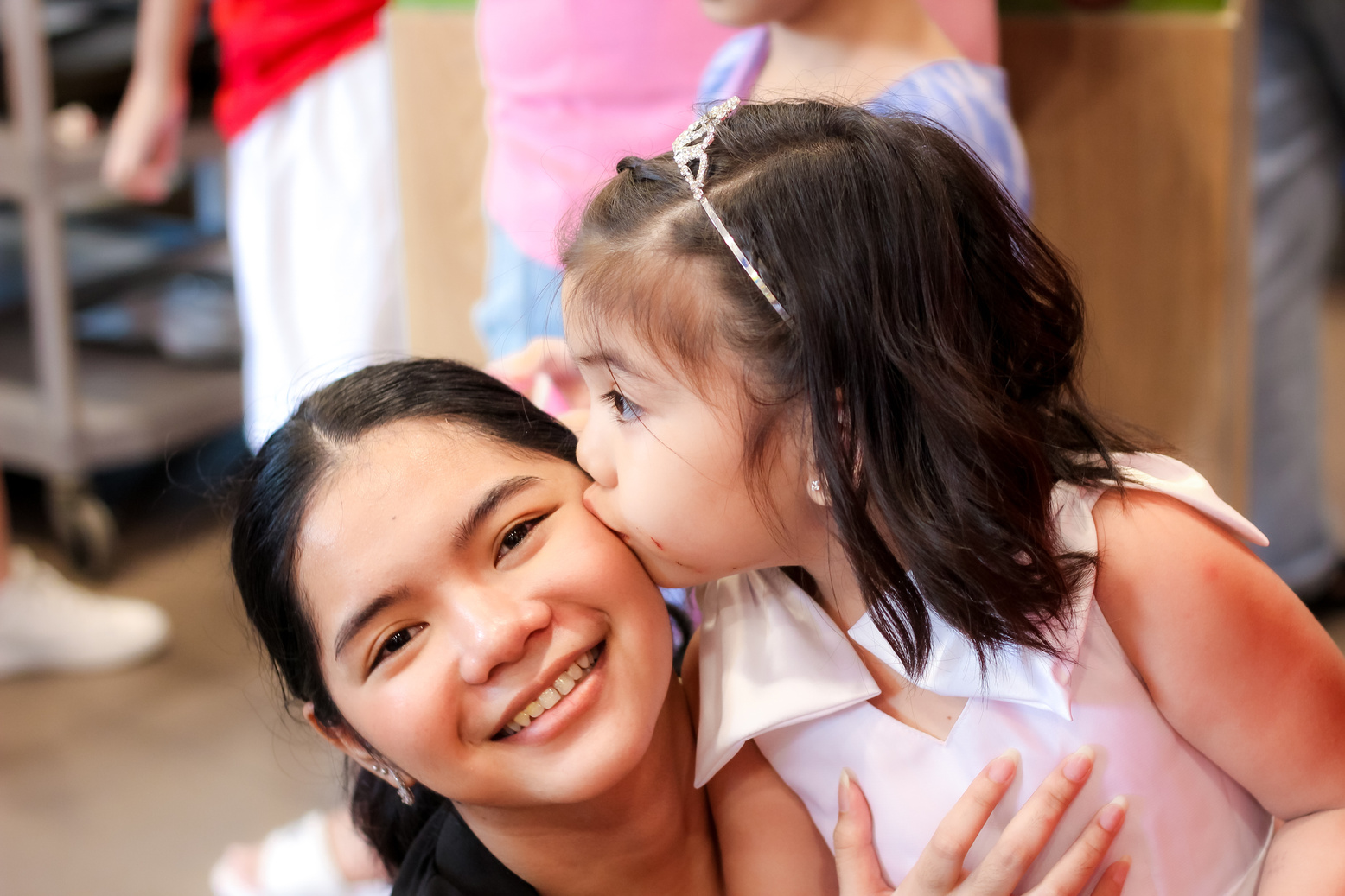 A kid kissing her sister on the cheeks